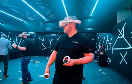 A man playing a VR escape game with his coworkers