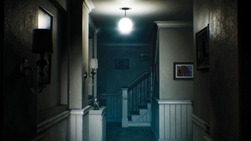 A dark, narrow hallway inside a haunted mansion featuring a single glowing orb light, eerie shadows, and a staircase leading to the upper floor.